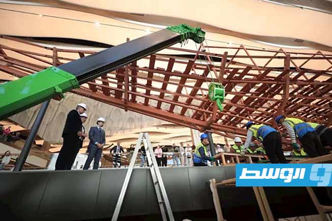 موظفو المتحف المصري الكبير أثناء تركيب ألواح خشبية أثرية من المركب الثاني للملك خوفو على إطار معدني، في 23 ديسمبر 2025.