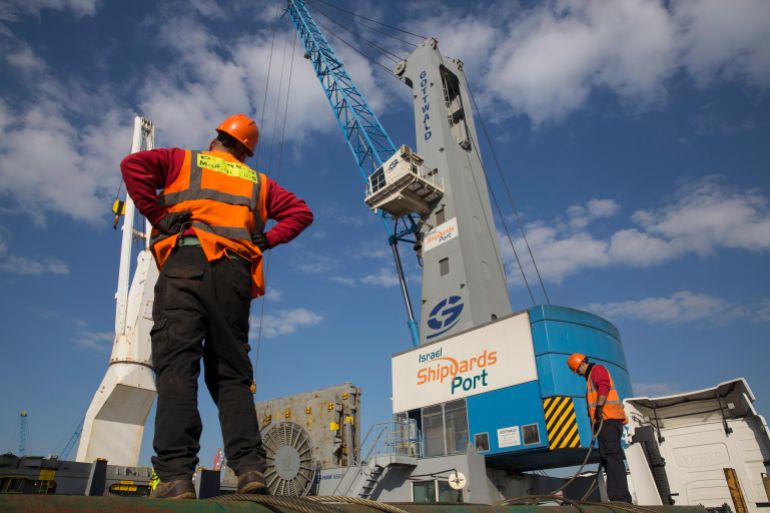 Workers load trucks at Israel Shipyards Port in Haifa February 5, 2014. Three years after Syria plunged into violence, Israel is reaping an unlikely economic benefit. Exports from Turkey have begun to flow through Israel and across the Sheikh Hussein Bridge to Jordan and a few Arab neighbours. The trade is growing enough to encourage long-held Israeli hopes that the Jewish state can become a commercial gateway to the Arab world. Picture taken February 5, 2014.