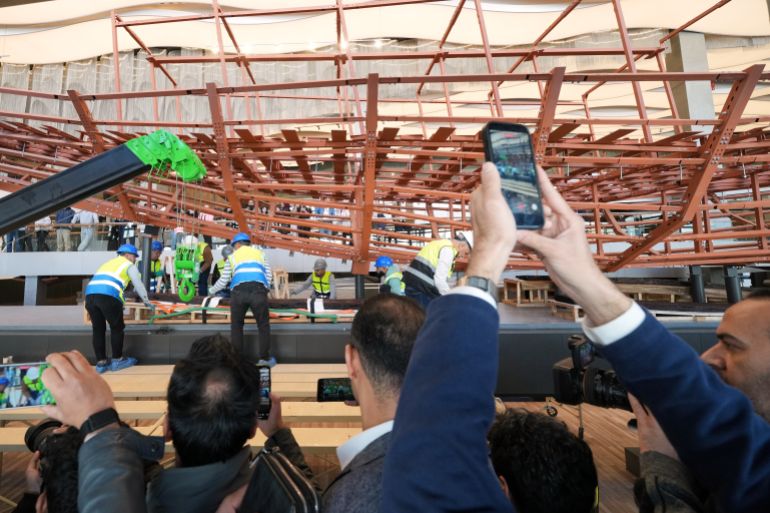 زوار يلتقطون صوراً لعلماء الآثار أثناء إعادة تجميع المركب الشمسي الثاني للملك خوفو