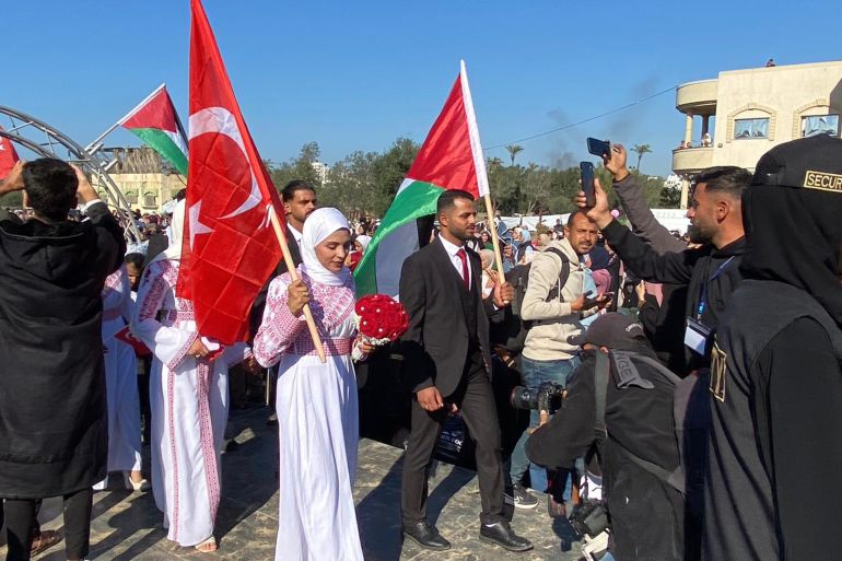 Brides and grooms carrying Palestinian and Turkish flags at a mass wedding ceremony in the town of Al-Zawaida, central Gaza Strip