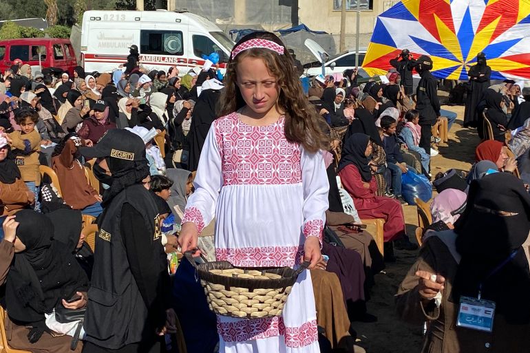 A girl wearing a Palestinian dress and holding a basket of roses at the mass wedding ceremony