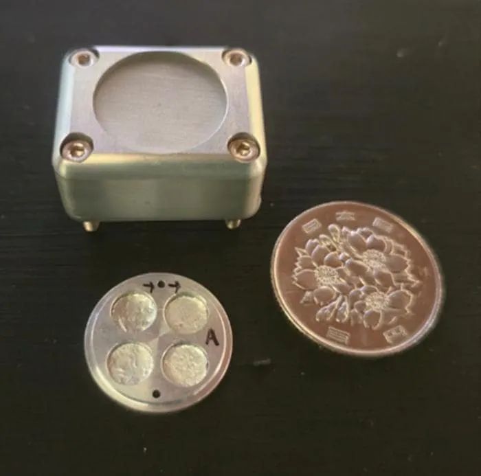 The space exposure unit used in the experiment, next to a 100-yen coin for scale.
