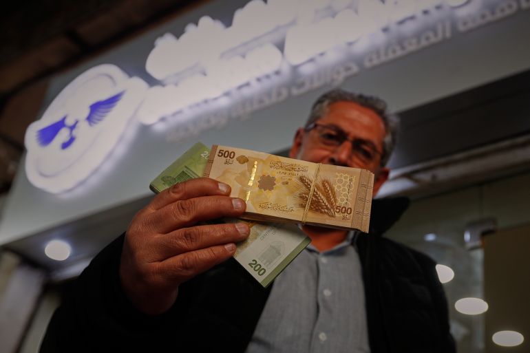 new Syria pound A man displays 500, and 200-pound notes from Syria's newly circulating currency outside a currency exchange office in Damascus, Syria, Saturday, Jan. 3, 2026. (AP Photo/Omar Sanadiki)