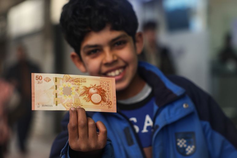 New Syrian Pound. A boy shows a newly issued 50-Syrian-pound banknote in Damascus, Syria, Saturday, Jan. 3, 2026.