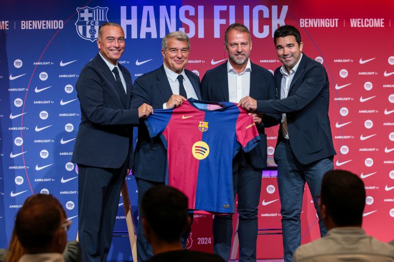 برشلونة، إسبانيا - 25 يوليو: المدرب الجديد لنادي برشلونة هانسي فليك، ورئيس النادي خوان لابورتا، والمدير الرياضي ديكو، ورافا يوستي يلتقطون صورة في ملعب سبوتيفاي كامب نو في 25 يوليو 2024 في برشلونة، إسبانيا.