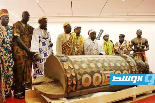 Ivorian officials stand before the 'Sacred Drum' after its restoration in Paris, during a ceremony hosted by the Quai Branly Museum in November 2022.