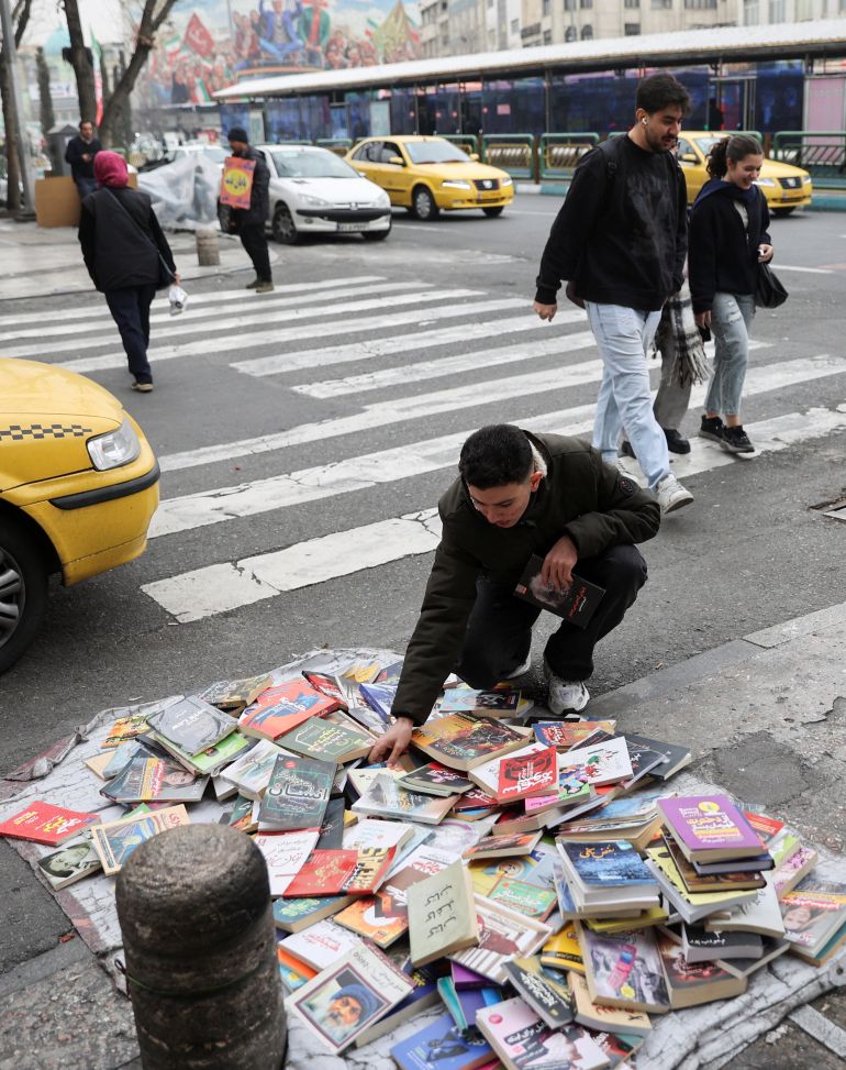 أشخاص يمشون بجوار كتب معروضة للبيع في الشارع، في طهران، إيران، 7 فبراير 2026. Majid Asgaripour/WANA (وكالة أنباء غرب آسيا) عبر رويترز انتباه المحررين - هذه الصورة مقدمة من طرف ثالث