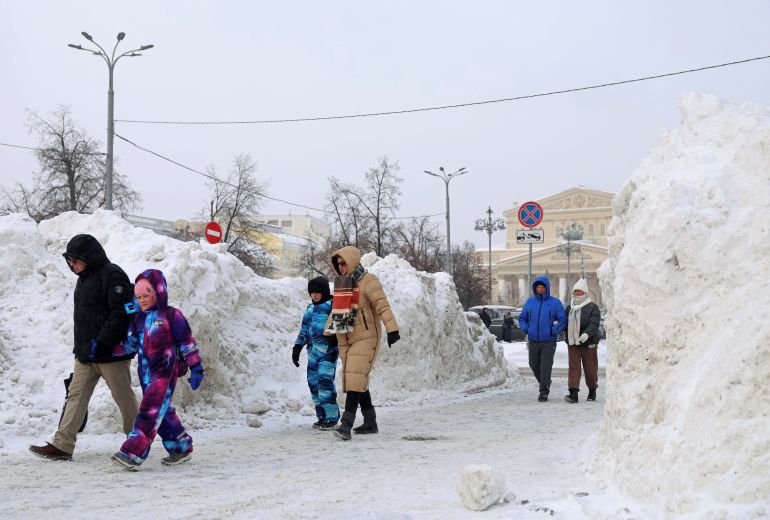 People walk past piles of snow near the Bolshoi Theatre in central Moscow, Russia February 1, 2026.